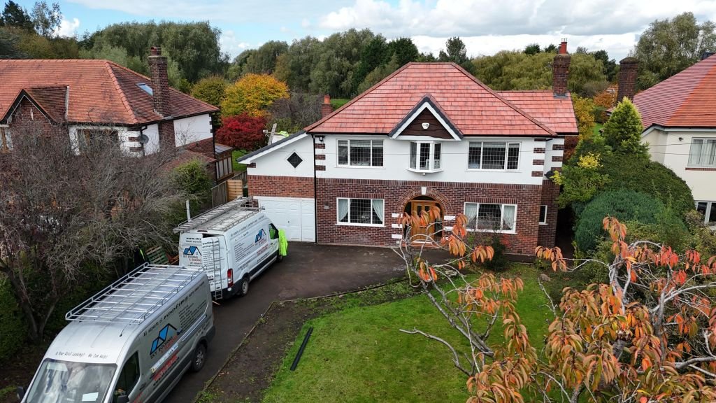 Red tiled roof on a detached house, with roofing vans on the driveway